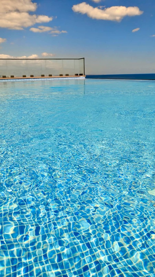 Crystal-clear water at the glass-railed edge of the rooftop pool